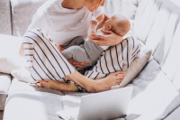 Young mother with her kid working at home on a computer